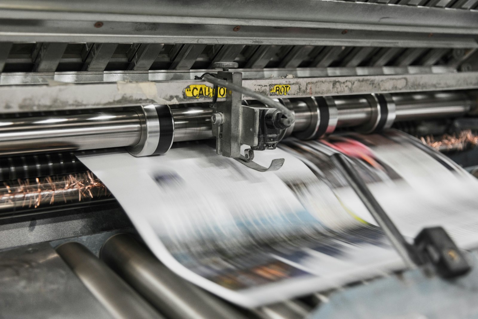 Folhas impressas passando por uma prensa de impressão